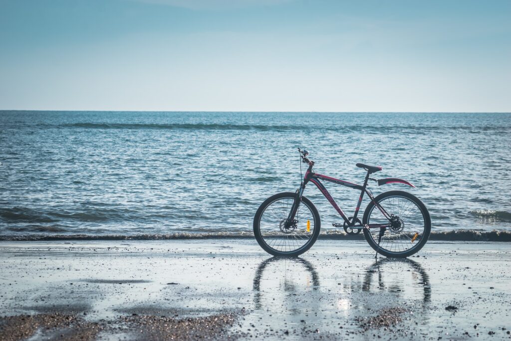 alquiler de bicicletas en valencia - bici roja con aleta en la playa