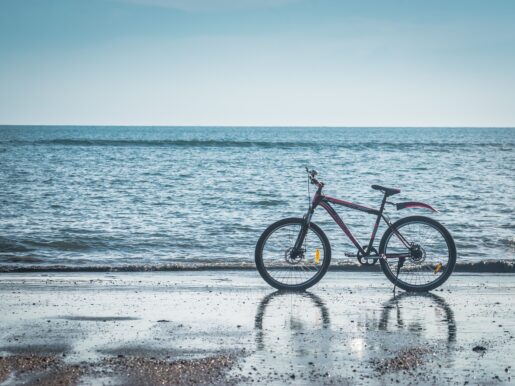 alquiler de bicicletas en valencia - bici roja con aleta en la playa