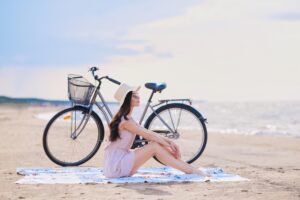 Descubrir la malvarrosa en bicicleta - chica gorro relajada en la playa